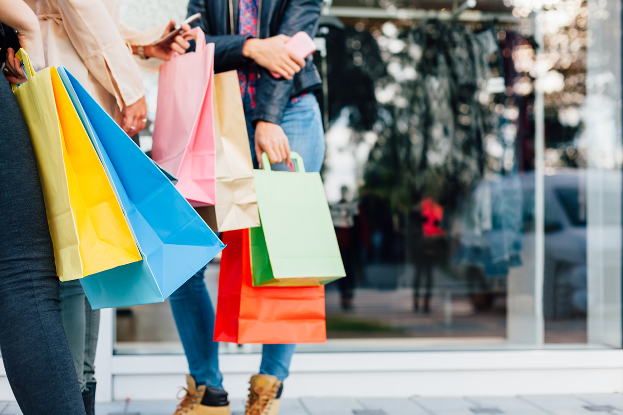 friends standing on line shopping with bags